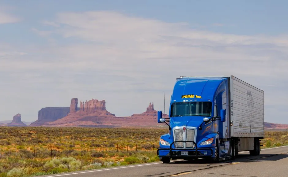 A blue semi truck driving down a desert highway